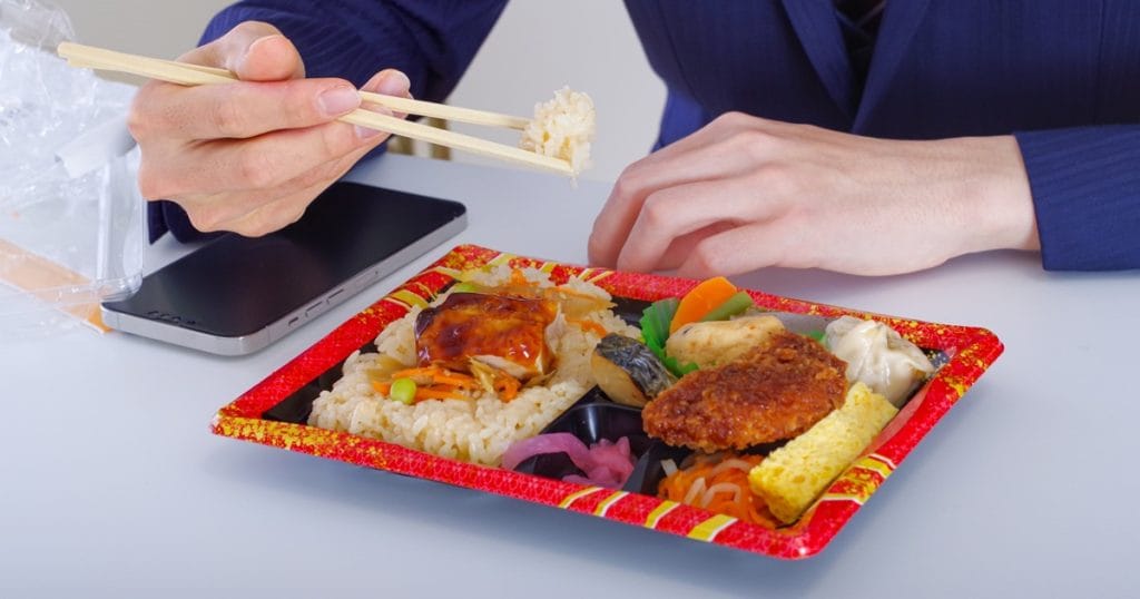 コンビニ弁当を食べる男性